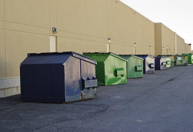 a construction worker unloading debris into a blue dumpster in Mundelein IL